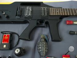 Items, prohibited on passenger airlines, and confiscated from passengers by Transportation Security Administration (TSA) officers, is displayed at Dulles International Airport in Dulles, Va., Tuesday, March 26, 2019. The items include a guitar shaped like a semi-automatic rifle, an inert grenade, and a stun gun. (AP Photo/Cliff Owen)