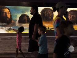 People walk past the faces of human ancestors as they visit the exhibits inside the Smithsonian Hall of Human Origins, Thursday, July 20, 2023, at the Smithsonian Museum of Natural History in Washington. More research is showing that we carry genes from other kinds of ancient humans, and their DNA affects our lives today. (AP Photo/Jacquelyn Martin)