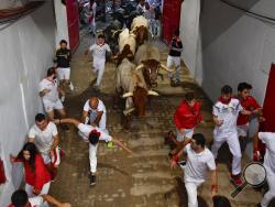 Revellers run next to fighting bulls during the running of the bulls at the San Fermin Festival, in Pamplona, northern Spain, Sunday, July 14, 2019. The San Fermin fiesta made internationally famous by Ernest Hemingway in his novel "The Sun Also Rises" draws around 1 million partygoers each year.(AP Photo/Alvaro Barrientos)