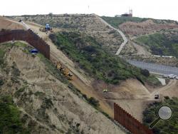 FILE - In this March 11, 2019 photo, construction crews replace a section of the primary wall separating San Diego, above right, and Tijuana, Mexico, below left, seen from Tijuana, Mexico. Defense Secretary Mark Esper has approved the use of $3.6 billion in funding from military construction projects to build 175 miles of President Donald Trump’s wall along the Mexican border. (AP Photo/Gregory Bull, File)