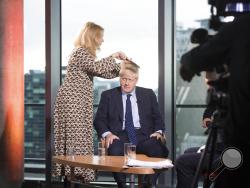 British Prime Minister Boris Johnson has his hair combed as he prepares to appear on a TV political show at Media City in Salford, England before opening the Conservative party annual conference Sunday Sept. 29, 2019. Johnson headed Sunday to the Conservative Party conference in Manchester, where the party is widely expected to endorse government plans to spend more on the country's National Health Service. (Stefan Rousseau/PA via AP)