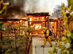 Woodbridge firefighter Joe Zurilgen passes a burning home as the Kincade Fire rages in Healdsburg, Calif., on Sunday, Oct 27, 2019. (AP Photo/Noah Berger)