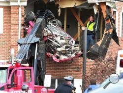 A Porsche is removed form the second story of a building after the convertible went airborne and crashed into the second floor of a New Jersey commercial building early Sunday, killing both of the car's occupants, in Toms River, N.J. (Ed Murray/NJ Advance Media via AP)