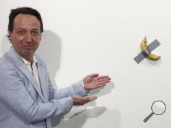 In this Dec. 4, 2019 photo, gallery owner Emmanuel Perrotin poses next to Maurizio Cattlelan's "Comedian" at the Art Basel exhibition in Miami Beach, Fla. The work sold for $120,000. (AP Photo/Siobhan Morrissey)