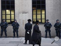 Orthodox Jewish men pass New York City police guarding a Brooklyn synagogue prior to a funeral for Mosche Deutsch, Wednesday, Dec. 11, 2019 in New York. Deutsch, a rabbinical student from Brooklyn, was killed Tuesday in the shooting inside a Jersey City, N.J. market. (AP Photo/Mark Lennihan)