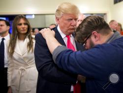 FILE - In this Jan. 31, 2016, file photo, Pastor Joshua Nink, right, prays for then Republican presidential candidate Donald Trump, as his wife, Melania, left, watches after a Sunday service at First Christian Church, in Council Bluffs, Iowa. In his first campaign move of the 2020 election year, President Donald Trump on Friday will launch a coalition of evangelicals as he aims to shore up and expand support from an influential piece of his political base. (AP Photo/Jae C. Hong, File)