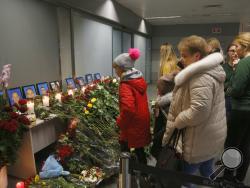 People look at a memorial at Borispil international airport outside in Kyiv, Ukraine, Thursday, Jan. 9, 2020, for the flight crew members of the Ukrainian 737-800 plane that crashed on the outskirts of Tehran. The crew of a Ukrainian jetliner that crashed in Iran, killing all 176 people on board, never made a radio call for help and was trying to turn back for the airport when the burning plane went down, an initial Iranian investigative report said Thursday. (AP Photo/Efrem Lukatsky)
