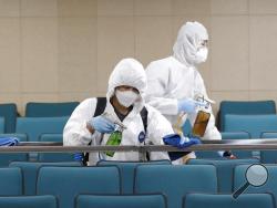 Workers in protective suits spray disinfectant as a precaution against the COVID-19 at an indoor gymnasium in Seoul, South Korea, Tuesday, Feb. 25, 2020. China and South Korea on Tuesday reported more cases of a new viral illness that has been concentrated in North Asia but is causing global worry as clusters grow in the Middle East and Europe. (AP Photo/Lee Jin-man)