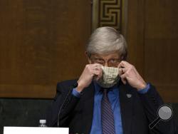 National Institutes of Health Director Dr. Francis Collins puts on his face mask after a Senate Health Education Labor and Pensions Committee hearing on new coronavirus tests on Capitol Hill in Washington, Thursday, May 7, 2020. (Anna Moneymaker/The New York Times via AP, Pool)