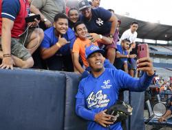 FILE - In this Jan. 11, 2020, file photo, Kansas City Royals' Salvador Perez takes a photograph with a fan's cellphone prior to an All-Star exhibition softball game at Rod Carew stadium in Panama City, Panama. When the virus wanes enough to allow the games to begin again, the very essence of these events will likely be missing. “You know how much I love to talk to the fans, you know? To be in conversation, to throw the ball to kids,” Kansas City Royals catcher Salvador Perez said. (AP Photo/Eric Batista, Fi