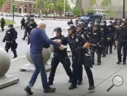In this image from video provided by WBFO, a Buffalo police officer appears to shove a man who walked up to police Thursday, June 4, 2020, in Buffalo, N.Y. Video from WBFO shows the man appearing to hit his head on the pavement, with blood leaking out as officers walk past to clear Niagara Square. Buffalo police initially said in a statement that a person “was injured when he tripped & fell,” WIVB-TV reported, but Capt. Jeff Rinaldo later told the TV station that an internal affairs investigation was opened