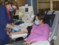 In this April 22, 2020 photo provided by New York Blood Center Enterprises, Aubrie Cresswell, 24, donates convalescent plasma at the Blood Bank of Delmarva Christiana Donor Center in suburban Newark, Del. “It’s, I think, our job as humans to step forward and help in society,” said Cresswell who has donated three times and counting. One donation was shipped to a hospitalized friend of a friend, and “it brought me to tears. I was like, overwhelmed with it just because the family was really thankful.” (New Yor