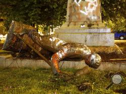A statue from the Richmond Howitzers Monument in Richmond, Va., lies after being toppled Tuesday night, June 16, 2020, in Richmond, Va. The monument was erected in 1892 to commemorate a Richmond Civil War artillery unit, (Alexa Welch Edlund/Richmond Times-Dispatch via AP)