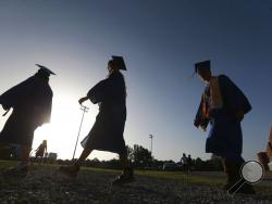 FILE - In this June 27, 2020, file photo, Saltillo High School seniors make their way to the football field as the sun begins to set for their graduation ceremony in Saltillo, Miss. The number of high school seniors applying for U.S. federal college aid plunged in the weeks following the sudden closure of school buildings this spring — a time when students were cut off from school counselors, and families hit with financial setbacks were reconsidering plans for higher education. (Thomas Wells/The Northeast 