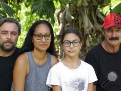 A group who have been stranded in Tahiti, pictured from left, Benjamin Baude, Kissy Ika Chavez Baude, Gaïa Baude Ika and Thierry Gourtay in Afareaitu on Moorea Island, Tahiti, Saturday, Sept. 19, 2020. A group of 25 residents from remote Easter Island has been stranded far from home for six months now. Many arrived in March planning to stay for just a few weeks. But they got stuck when the virus swept across the globe and their flights back home on LATAM airlines were canceled. LATAM says it doesn't know wh