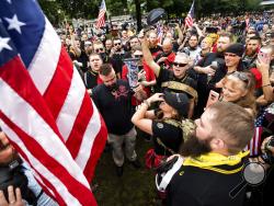 FILE - In this Aug. 17, 2019, file photo, members of the Proud Boys and other right-wing demonstrators plant a flag in Tom McCall Waterfront Park during a rally in Portland, Ore. At least several thousand people are expected in Portland on Saturday, Sept. 26, 2020, for a rally in support of President Donald Trump and his re-election campaign as tensions boil over nationwide following the decision not to charge officers in Louisville, Kentucky for killing Breonna Taylor. (AP Photo/Noah Berger, File)