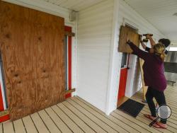 Residents Mamie Russo and her son Cole attach wood to their front door while preparing for Hurricane Delta on Thursday, Oct. 8, 2020, in Cypremort Point, La. (Brad Kemp/The Advocate via AP)