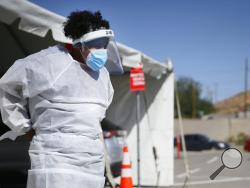 FILE - In this Oct. 26,2020, file photo, a medical worker stands at a COVID-19 state drive-thru testing site at UTEP, in El Paso, Texas. The U.S. has recorded about 10.3 million confirmed infections, with new cases soaring to all-time highs of well over 120,000 per day over the past week. (Briana Sanchez/The El Paso Times via AP, File)
