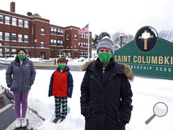 Head of School Jennifer Kowieski, right, poses with students Madeline Perry, of Brookline, Mass., left, and Landon Freytag, of Newton, Mass., center, outside the Saint Columbkille Partnership School, a Catholic school, Friday, Dec. 18, 2020, in the Brighton neighborhood of Boston. The families of both students decided to switch to the school, avoiding the challenges of remote learning at many public schools. (AP Photo/Charles Krupa)