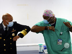 Surgeon General of the U.S. Jerome Adams, left, elbow-bumps Emergency Room technician Demetrius Mcalister after Mcalister got the Pfizer COVID-19 vaccination at Saint Anthony Hospital in Chicago, on Tuesday, Dec. 22, 2020. (Youngrae Kim/Chicago Tribune via AP, Pool)