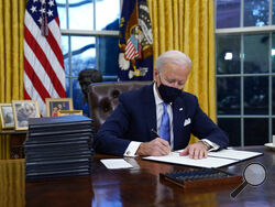 President Joe Biden signs his first executive order in the Oval Office of the White House on Wednesday, Jan. 20, 2021, in Washington. (AP Photo/Evan Vucci)