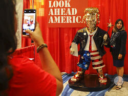 A woman takes a photo with a golden Donald Trump statue at the Conservative Political Action (CPAC) conference on Friday, Feb. 26, 2021, in Orlando, Fla. (Sam Thomas/Orlando Sentinel via AP)