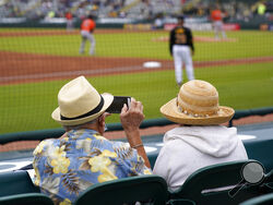 In this Monday, March 22, 2021 file photo, two older adults socially distanced, watch a spring training exhibition baseball game between the Pittsburgh Pirates and the Baltimore Orioles in Bradenton, Fla. Spring has arrived with sunshine and warmer temperatures, and many vaccinated seniors are emerging from COVID-19-imposed hibernation. (AP Photo/Gene J. Puskar, File)