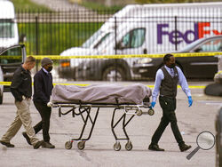 A body is taken from the scene where multiple people were shot at a FedEx Ground facility in Indianapolis, Friday, April 16, 2021. A gunman killed several people and wounded others before taking his own life in a late-night attack at a FedEx facility near the Indianapolis airport, police said. (AP Photo/Michael Conroy)