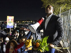 AP Photo/John Minchillo Michael Odiari leads a chant as he attempts to deescalate an altercation between demonstrators and police during a protest decrying the shooting death of Daunte Wright outside the Brooklyn Center Police Department Friday in Brooklyn Center, Minn.