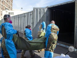 FILE - This Jan. 12, 2021, file photo provided by the LA County Dept. of Medical Examiner-Coroner shows National Guard members assisting with processing COVID-19 deaths and placing them into temporary storage at LA County Medical Examiner-Coroner Office in Los Angeles. Just a few months ago, California was the epicenter of the coronavirus pandemic in the U.S. Now as cases spike in other parts of the country, California has gone from worst to first with the lowest infection rate in the U.S. even as it moves 