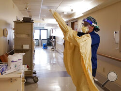 Registered Nurse Monica Quintana dons protective gear before entering a room at the William Beaumont hospital, April 21, 2021 in Royal Oak, Mich. Beaumont Health warned that its hospitals and staff had hit critical capacity levels. Michigan has become the current national hotspot for COVID-19 infections and hospitalizations at a time when more than half the U.S. adult population has been vaccinated and other states have seen the virus diminish substantially. Beaumont Health warned that its hospitals and sta