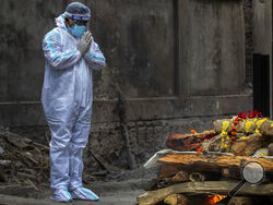 A relative in protective suit performs last rituals as the body of a person who died of COVID-19 is cremated in Gauhati, India, Monday, May 24, 2021. India crossed another grim milestone Monday of more than 300,000 people lost to the coronavirus as a devastating surge of infections appeared to be easing in big cities but was swamping the poorer countryside. (AP Photo/Anupam Nath)