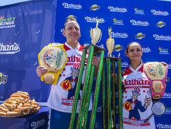 Winners Joey Chestnut and Michelle Lesco pose with their championship belts and trophies at the Nathan's Famous Fourth of July International Hot Dog-Eating Contest in Coney Island's Maimonides Park on Sunday, July 4, 2021, in Brooklyn, New York. (AP Photo/Brittainy Newman)