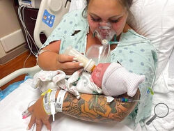 This July 27, 2021, photo provided by Melissa Syverson shows West Melbourne resident Kristen McMullen, 30, feeding her newborn daughter, Summer, at Holmes Regional Medical Center in Melbourne, Fla. Kristen only got to hold Summer for a few moments after giving birth via emergency C-section. The mother, who had COVID-19, was then taken to the ICU, where her condition worsened. She died on Aug. 6, 2021, 10 days after her little girl was born. (Melissa Syverson via AP)