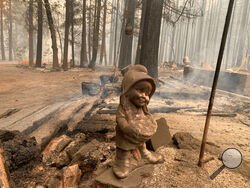 A surviving ceramic statue is seen outside a house that burned along North Arm Road in Plumas County near Taylorsville, Calif., Sunday, Aug. 15, 2021. Thousands of Northern California homes remain threatened by the nation's largest wildfire and officials warn the danger of new blazes erupting across the West is high because of unstable weather. (AP Photo/Eugene Garcia)