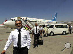 Pilots of Ariana Afghan Airlines walk on the tarmac after landing at Hamid Karzai International Airport in Kabul, Afghanistan, Sunday, Sept. 5, 2021. Some domestic flights have resumed at Kabul's airport, with the state-run Ariana Afghan Airlines operating flights to three provinces. (AP Photo/Wali Sabawoon)