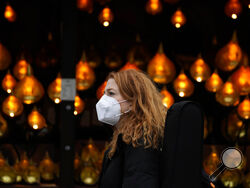 A woman wears a face covering as she passes a Christmas lights, in London, Wednesday, Dec. 22, 2021. British Prime Minister Boris Johnson said on Monday that his government reserves the "possibility of taking further action" to protect public health as Omicron spreads across the country. (AP Photo/Frank Augstein)