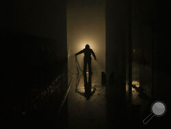 A Ukrainian firefighter drags a hose inside a large food products storage facility which was destroyed by an airstrike in the early morning hours in Brovary, north of Kyiv, Ukraine, Sunday, March 13, 2022. Waves of Russian missiles pounded a military training base close to Ukraine's western border with NATO member Poland, killing 35 people, following Russian threats to target foreign weapon shipments that are helping Ukrainian fighters defend their country against Russia's grinding invasion.(AP Photo/Vadim 