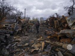 A man carries bicycle along a street filled with destroyed Russian military vehicles near Chernihiv, Ukraine, Sunday, April 17, 2022. Witnesses said multiple explosions believed to be caused by missiles struck the western Ukrainian city of Lviv early Monday as the country was bracing for an all-out Russian assault in the east. (AP Photo/Evgeniy Maloletka)