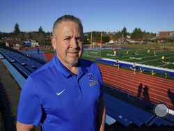 Joe Kennedy, a former assistant football coach at Bremerton High School in Bremerton, Wash., poses for a photo March 9, 2022, at the school's football field. After losing his coaching job for refusing to stop kneeling in prayer with players and spectators on the field immediately after football games, Kennedy will take his arguments before the U.S. Supreme Court on Monday, April 25, 2022, saying the Bremerton School District violated his First Amendment rights by refusing to let him continue praying at midf