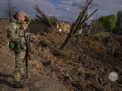 A Ukrainian serviceman inspects a site after an airstrike by Russian forces in Bahmut, Ukraine, Tuesday, May 10, 2022. (AP Photo/Evgeniy Maloletka)