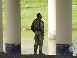 FILE - A member of the Texas National Guard looks across the Rio Grande to Mexico from the U.S. at Eagle Pass, Texas, on Aug. 26, 2022. At least eight migrants were killed as dozens attempted a hazardous crossing of the Rio Grande near Eagle Pass, Texas, officials said Friday, Sept. 2, 2022. U.S. Customs and Border Protection reported that it responded to the report a day earlier. (AP Photo/Eric Gay, File)
