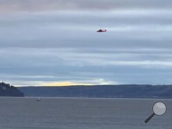 A Coast Guard helicopter searches the area where a floatplane crashed near Whidbey Island, Wash., Sunday, Sept. 4, 2022. (Courtney Riffkin/The Seattle Times via AP)