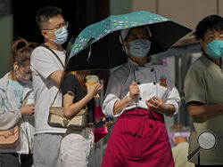 People wearing face masks wait in line to get their routine COVID-19 throat swabs at a coronavirus testing site in Beijing, Monday, Sept. 5, 2022. (AP Photo/Andy Wong)