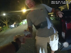 In this image from video provided by the Tampa Police Department, Joseph Ruddy, a prosecutor with the U.S. Attorney’s Office in Tampa, hands his business card to Officer Taylor Grant, outside his home in Temple Terrace, Fla., on the evening of July 4, 2023. When police arrived at his house to investigate a hit-and-run, Ruddy, one of the nation’s most prolific federal narcotics prosecutors, was so drunk he could barely stand up straight, leaning on the tailgate of his pickup to keep his balance. (Officer Tay