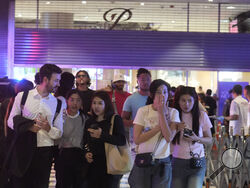 Visitors evacuate from a shopping mall in Bangkok, Thailand, Tuesday, Oct. 3, 2023. Hundreds of shoppers fled the major shopping mall in the center of the Thai capital Bangkok on Tuesday afternoon after what sounded like gunshots were heard inside. (AP Photo/Sakchai Lalit)