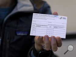 FILE - A nurse practitioner holds a COVID-19 vaccine card at a New York Health and Hospitals vaccine clinic in the Brooklyn borough of New York on Jan. 10, 2021. Now that COVID-19 vaccines are being distributed through the commercial markets instead of by the federal government in 2023, the Centers for Disease Control and Prevention won't be shipping out any more new cards. (AP Photo/Craig Ruttle, File)