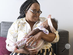 Asian Davis, 33, of Sikeston, Mo., cradles her 8-month-old daughter, Mira White during an interview on Oct. 3, 2023, in St. Louis. Davis and her lawyers say Mira suffered brain damage in March after developing bacterial meningitis tied to powdered infant formula contaminated with Cronobacter sakazakii, a germ known to cause severe disease in young babies. (AP Photo/Michael Thomas)