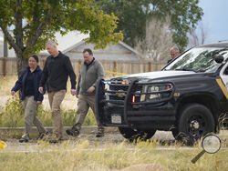 Authorities walk outside a closed funeral home where 115 bodies have been stored, Friday, Oct. 6, 2023, in Penrose, Colo. Authorities are investigating the improper storage of human remains at the southern Colorado funeral home that performs "green" burials without embalming chemicals or metal caskets. (AP Photo/David Zalubowski)