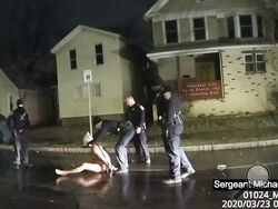 FILE- This image from police body camera video provided by Roth and Roth LLP, shows a Rochester police officer as he puts a hood over the head of Daniel Prude in Rochester, N.Y., March 23, 2020. Prude died after police held him down until he stopped breathing after encountering him running naked through the snowy streets of Rochester, NY. On Thursday, Oct. 12, 2023, a leading doctors group has formally withdrawn its approval of a 2009 paper on “excited delirium,” a document that critics say has been used to